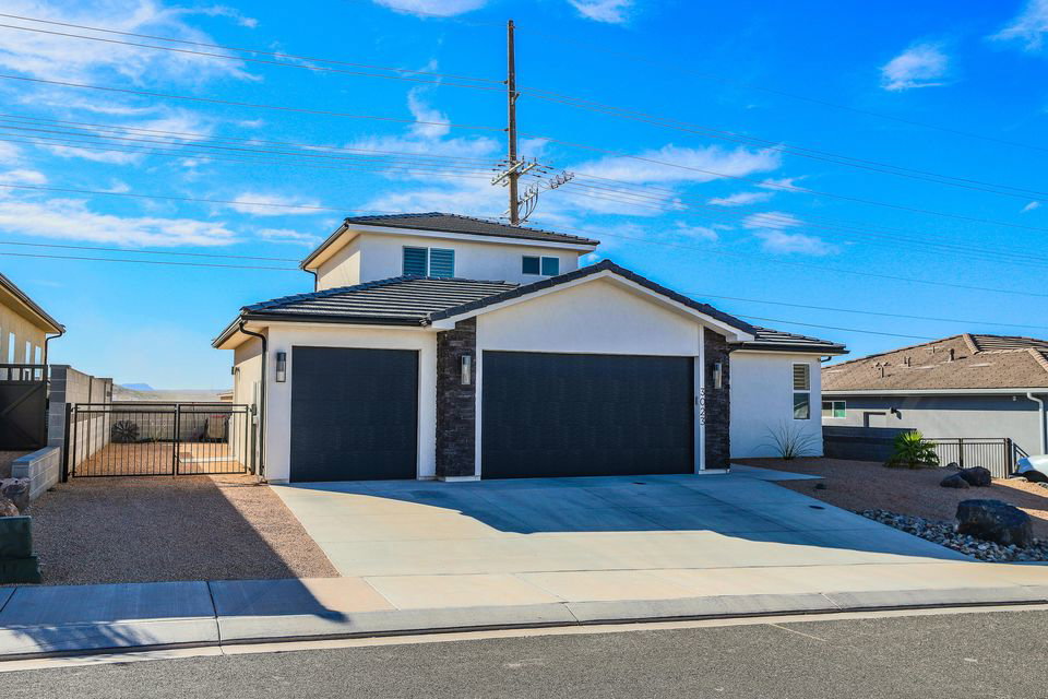 View of front of house with stucco siding, a tile roof, and driveway
