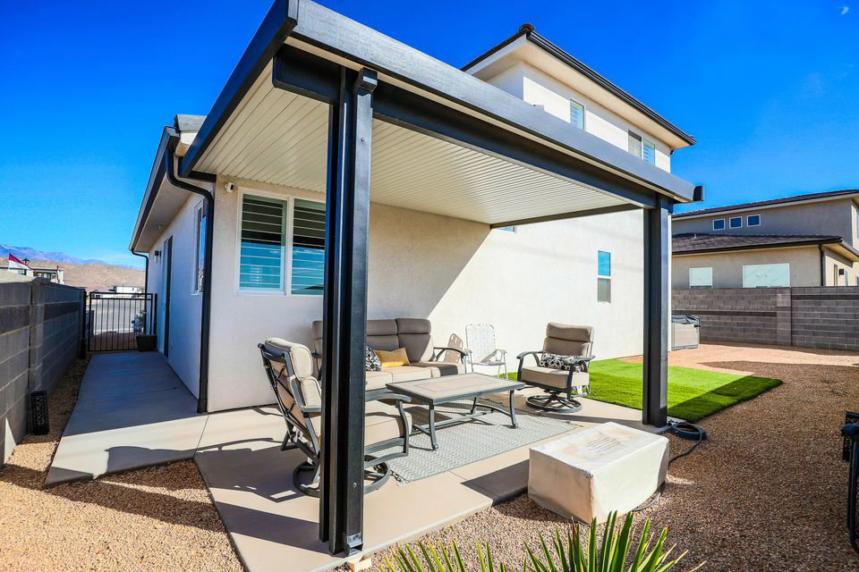 Back of house with outdoor lounge area, a patio, a gate, and stucco siding