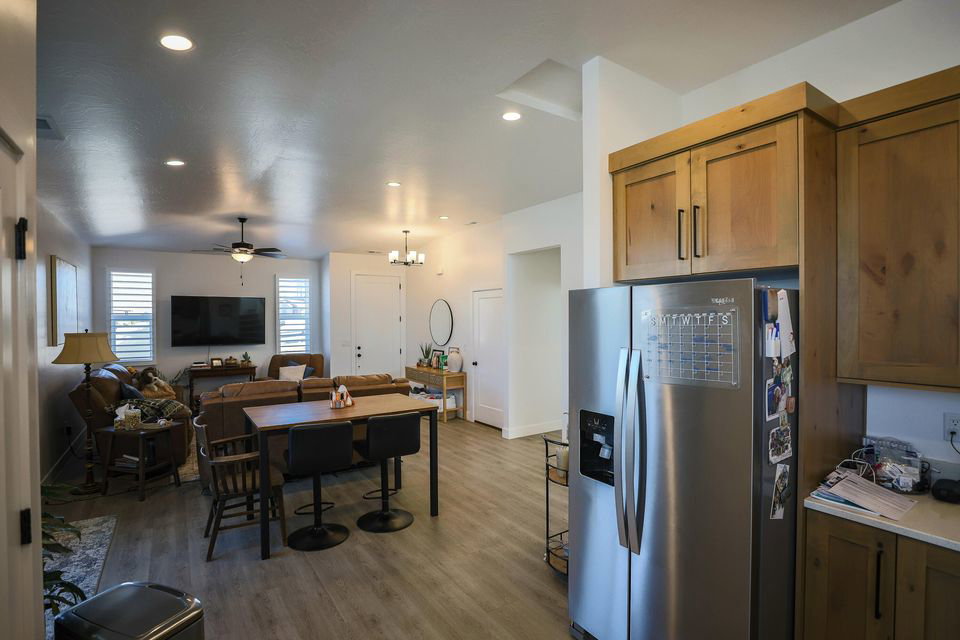Kitchen with stainless steel fridge with ice dispenser, open floor plan, brown cabinetry, light wood-style flooring, and a chandelier