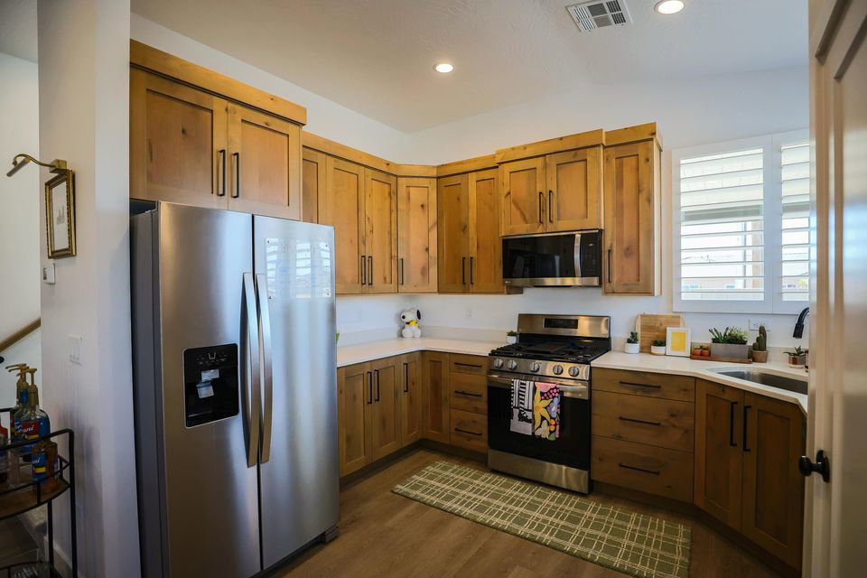 Kitchen with appliances with stainless steel finishes, brown cabinets, dark wood finished floors, and recessed lighting
