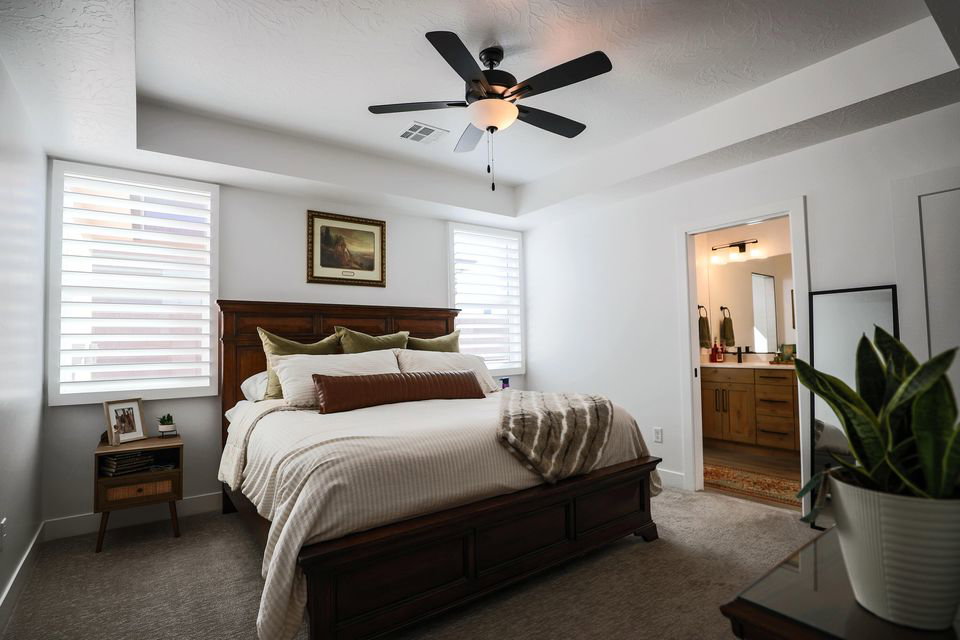 Bedroom with a tray ceiling, carpet flooring, a ceiling fan, and connected bathroom