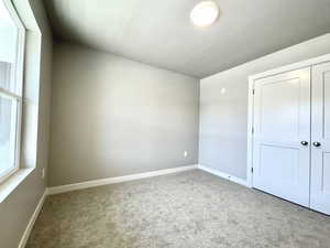 Unfurnished bedroom with carpet floors, multiple windows, and a closet