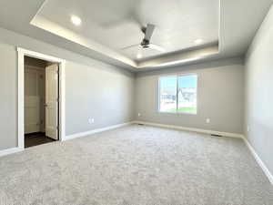 Unfurnished bedroom featuring a raised ceiling, a ceiling fan, carpet flooring, and recessed lighting