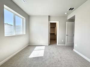Unfurnished bedroom featuring a spacious closet and light colored carpet