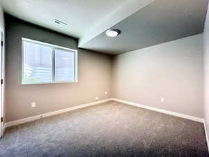 Carpeted spare room featuring baseboards and a textured ceiling