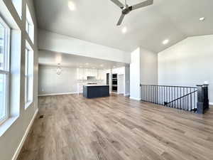 Unfurnished living room with a chandelier, recessed lighting, light wood-style floors, a ceiling fan, and lofted ceiling