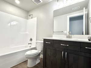 Bathroom with vanity, shower / bath combination, and dark wood-style floors