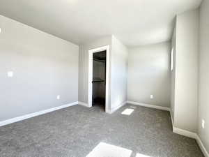 Unfurnished bedroom with a spacious closet and carpet