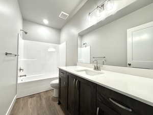 Bathroom with shower / bath combination, vanity, and dark wood-style flooring