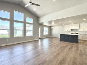 Unfurnished living room featuring a chandelier, dark wood-type flooring, vaulted ceiling, a ceiling fan, and recessed lighting