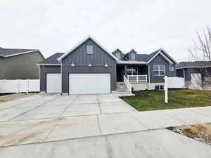 View of front of house featuring board and batten siding, a porch, driveway, and an attached garage