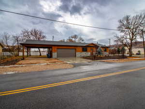 Ranch-style house featuring stone siding, a carport, concrete driveway, and an attached garage