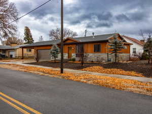 View of front of house featuring stone siding, driveway, a garage, and a shingled roof