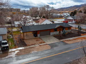 View of front facade featuring concrete driveway, roof with shingles, stone siding, a mountain view, and an attached garage