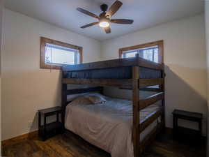 Bedroom featuring dark wood finished floors, multiple windows, and ceiling fan