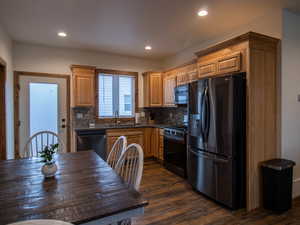 Kitchen featuring stainless steel appliances, backsplash, dark wood-style flooring, recessed lighting, and light brown cabinetry