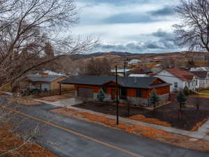View of front facade featuring driveway, a mountain view, stone siding, and a residential view