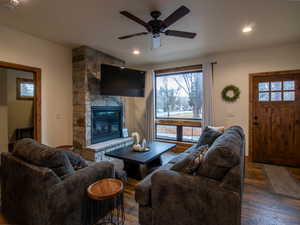 Living area with dark wood-style floors, a fireplace, a ceiling fan, and recessed lighting