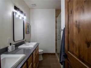 Primary Bathroom featuring a shower stall, double vanity, and wood tiled floors