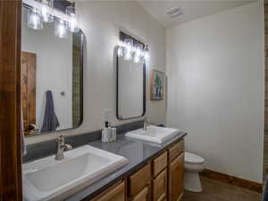 Primary Bathroom with double vanity and dark wood finished floors
