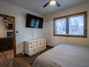 Primary Bedroom featuring dark wood finished floors, a ceiling fan, and a fireplace