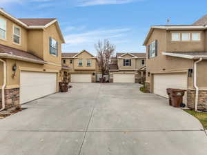 View of side of home with stucco siding, stone siding, a residential view, and driveway