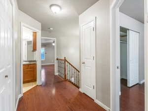 Hall with an upstairs landing, dark wood-type flooring, and a textured ceiling