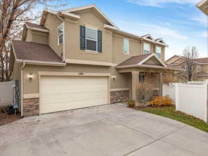 Traditional-style home with stucco siding, stone siding, concrete driveway, an attached garage, and roof with shingles