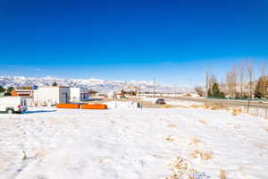 Yard covered in snow featuring a mountain view