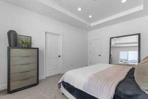 Carpeted bedroom with a tray ceiling and recessed lighting