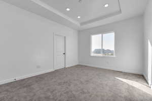 Carpeted empty room with a tray ceiling and recessed lighting