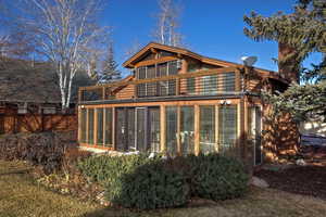 Back of property featuring a sunroom, a balcony, and a chimney