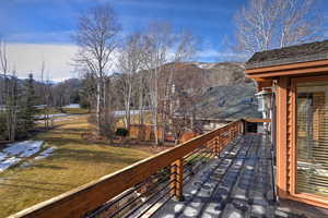 Snow covered deck with a yard, a balcony, and a mountain view