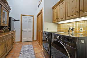 Laundry area with cabinet space, washing machine and dryer, and light tile patterned flooring