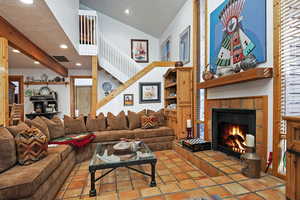 Living area featuring a fireplace, recessed lighting, high vaulted ceiling, and tile patterned flooring