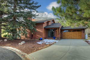 Rustic home with roof with shingles, concrete driveway, a garage, and a chimney