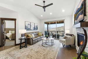 Living area featuring vaulted ceiling, dark wood-style flooring, a glass covered fireplace, recessed lighting, and a ceiling fan