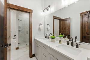 Bathroom with light marble finish flooring, double vanity, and a marble finish shower