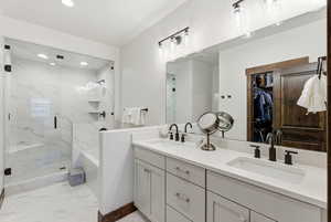 Full bath featuring a spacious closet, double vanity, a bath, a marble finish shower, and light marble finish flooring