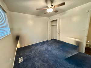 Unfurnished bedroom featuring a ceiling fan, carpet flooring, a textured ceiling, and a closet