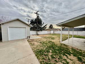 Fenced backyard featuring a patio, an outdoor structure, driveway, and a garage
