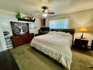 Carpeted bedroom with a textured ceiling and ceiling fan