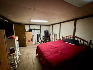 Carpeted bedroom with a drop ceiling and a textured wall