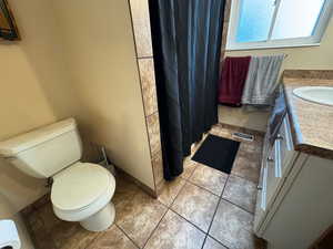 Full bath with vanity, a shower with shower curtain, and light tile patterned flooring