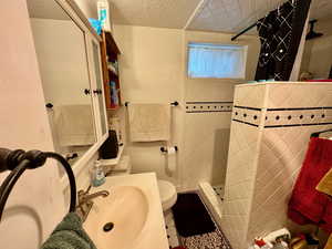 Bathroom featuring a tile shower, vanity, and a textured ceiling
