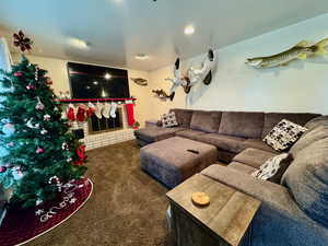 Living room with a brick fireplace, dark carpet, and a textured ceiling