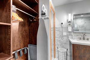 Bathroom featuring tile walls, vanity, a marble finish shower, and a wainscoted wall
