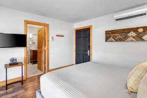 Bedroom featuring a wall unit AC and wood finished floors