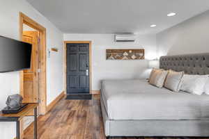 Bedroom with wood finished floors, recessed lighting, and a wall unit AC