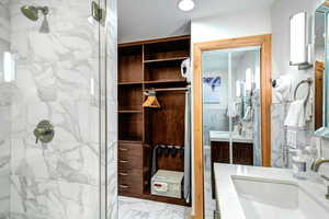 Bathroom with vanity, light marble finish flooring, and a marble finish shower